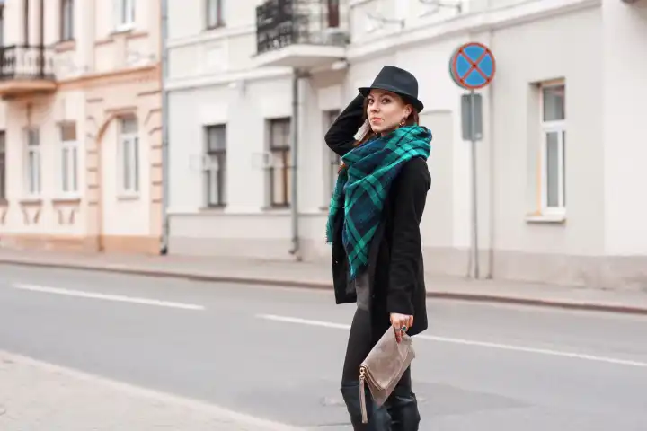 Porträt einer schönen Frau mit Schal und Hut am Straßenrand.
