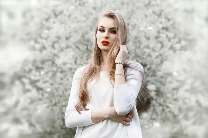 Porträt einer jungen Frau in der Nähe eines blühenden Baumes. Rote Lippen.