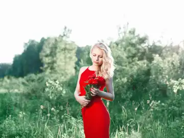 Junge schöne glückliche Frau mit Blumen auf einem Feld, Sommer im Freien.