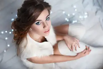 Junge hübsche Frau in einem weißen gestrickten Socken sitzen auf dem Boden auf einem Hintergrund von Lichtern... Ansicht von oben