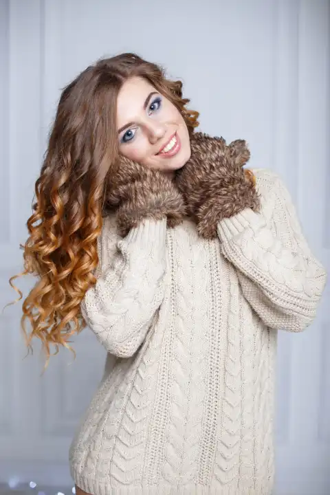 Beautiful cheerful girl with amazing smile in a warm sweater and mittens