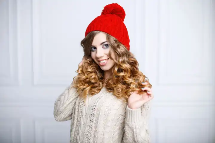 Hübsche Frau mit einem schönen Lächeln in einer roten Mütze und einem Strickpullover