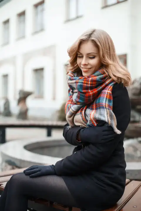 Beautiful girl in autumn clothes resting on a bench