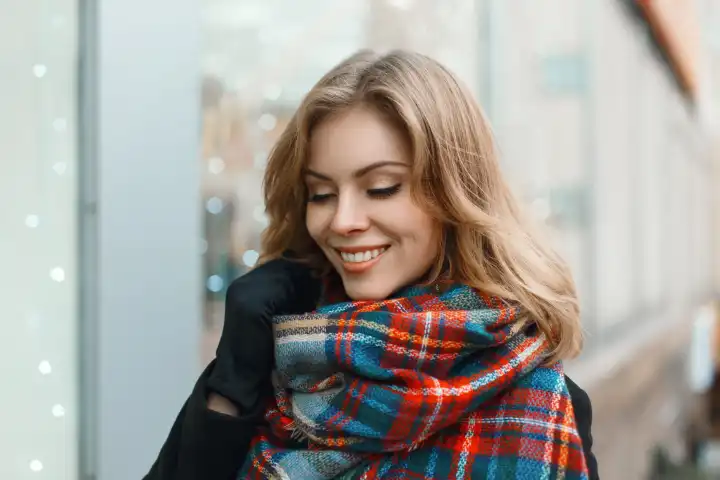 Junge schöne Mädchen mit einem Lächeln in Vintage-Schal und schwarzen Mantel auf dem Hintergrund der Schaufenster