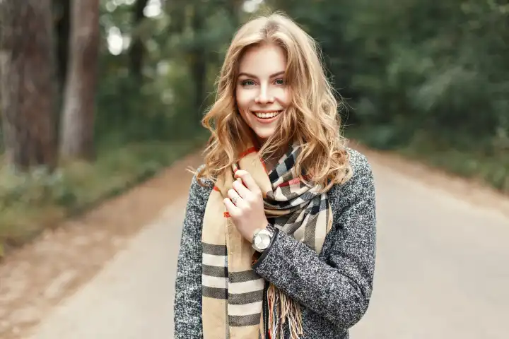 Fröhliches Lifestyle-Porträt eines schönen jungen Models mit einem süßen Lächeln in einem warmen Herbstschal.