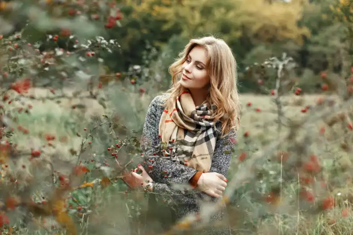 Hübsche Frau in Herbstkleidung posiert im Garten.