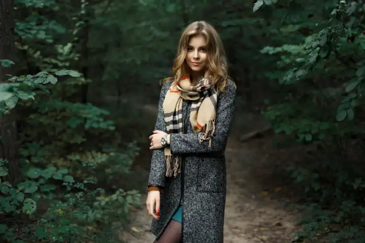 Schönes Mädchen in Mantel und Schal in einem dunklen Wald