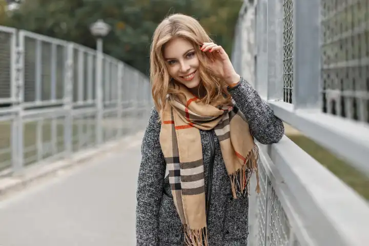 Schönes junges Mädchen mit einem Lächeln in einem warmen Schal und Mantel im Herbst Tag.