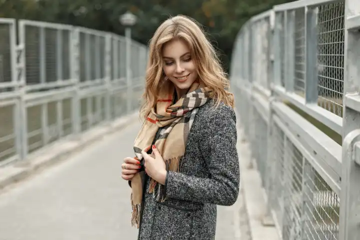 Schöne glückliche junge Frau in einem Herbstmantel mit Schal.