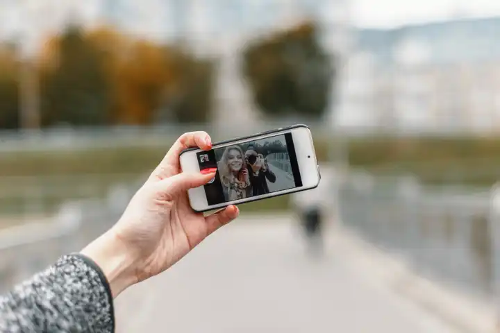 Schönes Mädchen mit Freund Fotografen zu nehmen Fotos auf dem Handy