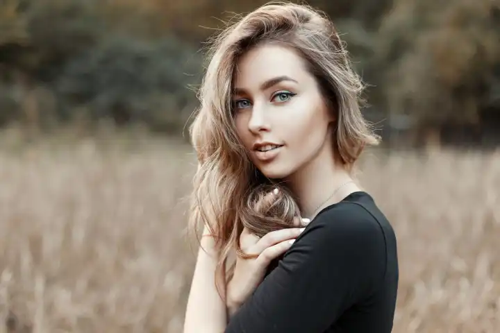 Porträt einer jungen Frau im schwarzen Hemd vor einem natürlichen Hintergrund