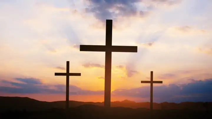 Kreuzigung von Jesus Christus in der Morgendämmerung - drei Kreuze bei Sonnenuntergang. Drei Kreuze stehen auf einem Feld vor einem schönen Himmel mit Strahlen und Wolken. Ostern