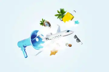 Creative blue loudspeaker with airplane, clouds, compass, luggage, bag, glasses, palm trees and swimsuit. Travel, creative idea. Advertising and attracting attention. Summer time
