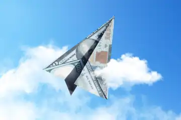 Papierflugzeug 100 Dollar fliegt in den Himmel mit Wolken, kreative Idee. Startup und Investitionsfinanzierung, Konzept. Versicherung und Einlagen
