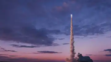 Weltraumrakete mit Rauch und Explosion wird erfolgreich in den rosa Abendhimmel mit Wolken abheben. Weltraummission und erfolgreicher Start. Rakete hebt ab