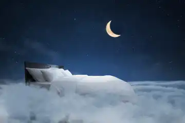 Bett mit Kissen und eine Decke fliegt in den Wolken mit einer Nacht Sternenhimmel mit dem Mond, kreative Idee. Süßer Traum, Konzept. Nachtruhe