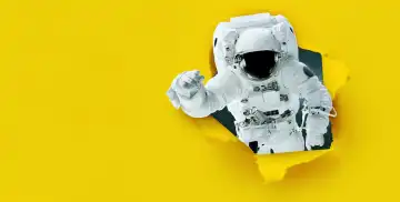 Space Mann Astronaut reißt Papier aus Loch, Konzept. Gelbes Banner für Design und Text. Kreative Idee. Reise in den Weltraum
