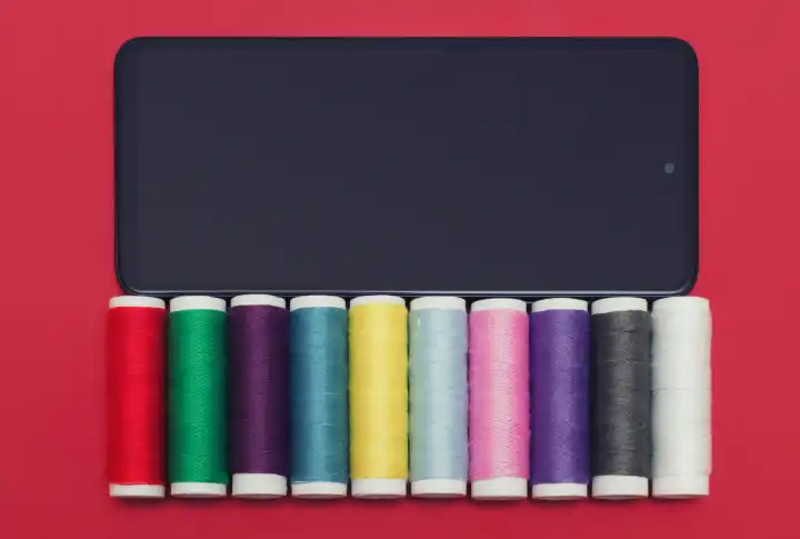 Colorful threads. Smartphone with a set of woolen items. Screen to display hobby and a craft clothing brand.
