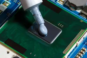 Thermal paste compound squeezing on processor of notebook. Thermal grease for better CPU cooling.