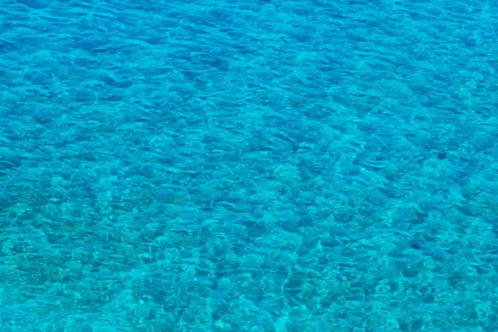 Lebendige blaue Oberfläche des Meeres. Draufsicht auf sauberes himmelblaues Meerwasser mit kleinen Wellen. Sommer Meerwasser Textur Hintergrund