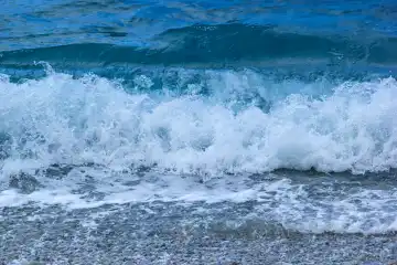 Sea water splash with foam. Wave on sand of beach from blue sea.