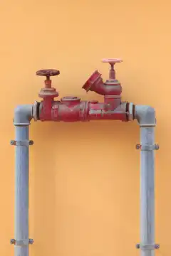 The outdoor water hydrant. Red pipe with valve equipment.