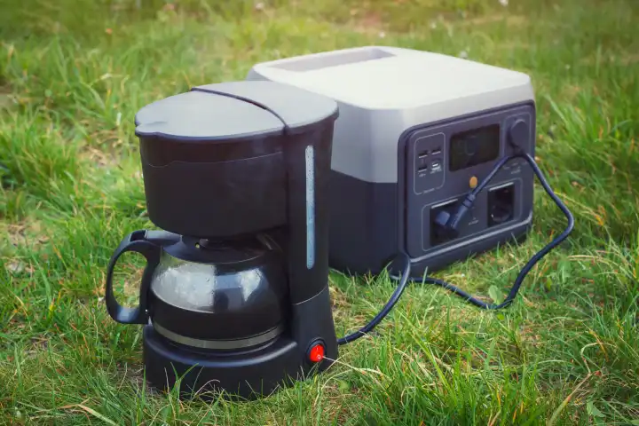 Kochen von gemahlenem Kaffee mit einem elektrischen Tropfer und einem tragbaren Kraftwerk. Die Wartung oder Campingausrüstung.