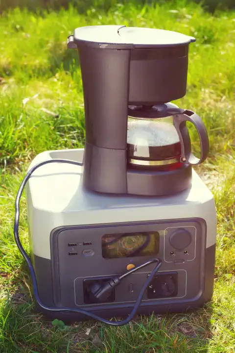 Der tragbare Power-Akku mit elektrischer Tropfkaffeemaschine. Morgendlicher Aromakaffee im Camp mit Sonnenlicht.