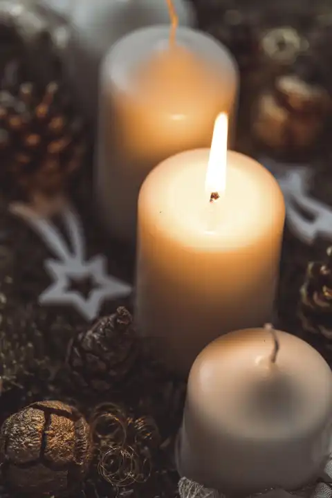 Die erste Kerze brennt auf einem Adventskranz am ersten Sonntag im Advent. Kerzenlicht, brennende Kerze an Weihnachten
