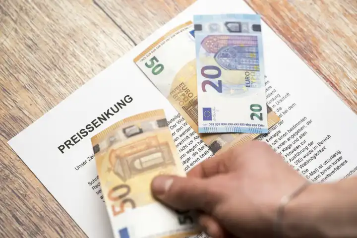 Symbolbild Preissenkung - Euro Geldscheine mit einem Schreiben mit Überschrift: Preissenkung