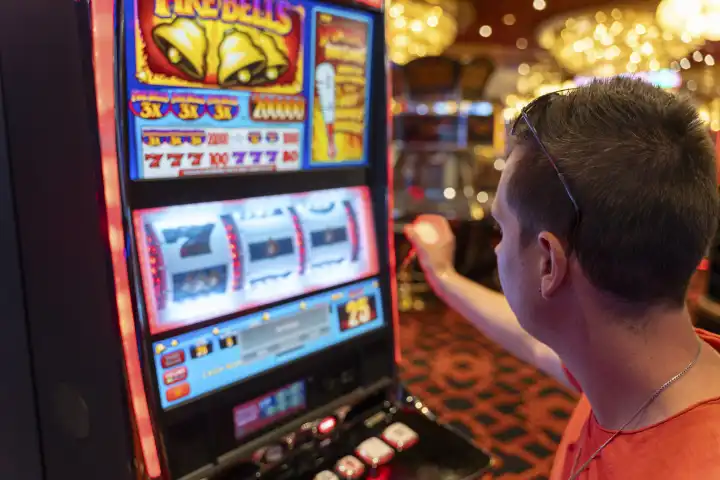 Ein junger Mann spielt an einem Spielautomaten in einem Casino. Symbolbild Glücksspiel