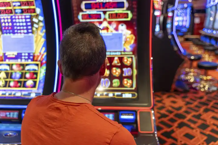 Ein junger Mann spielt an einem Spielautomaten in einem Casino. Symbolbild Glücksspiel