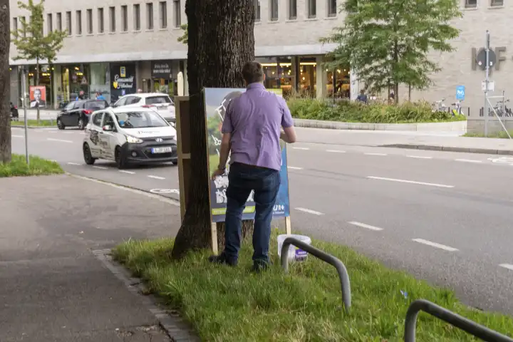 Ein Mann übermalt ein Wahlplakat der CSU für die Landtagswahl 2023 in Bayern. Vandalismus und Schmierereien an Wahlplakaten