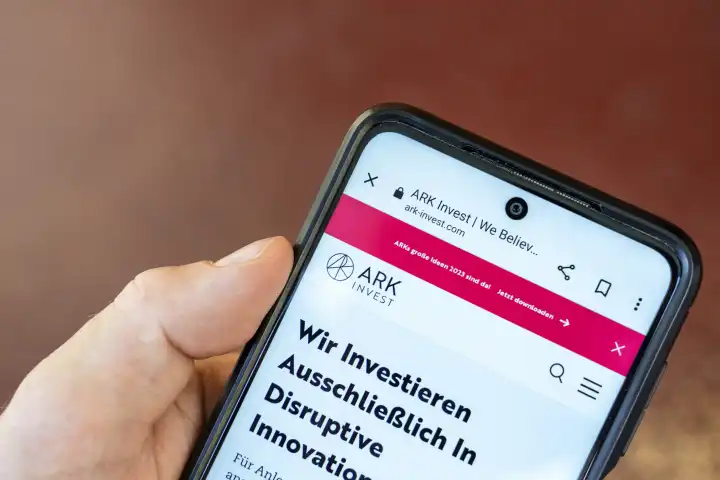 6 August 2023: Hand holding smartphone with ARK Invest (ARK Investment Management LLC) website. Investment company founded by Cathie Wood