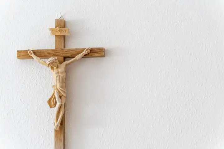 15 August 2023: A wooden Christian cross with a figure of Jesus and the inscription INRI hangs in a room on a white wall