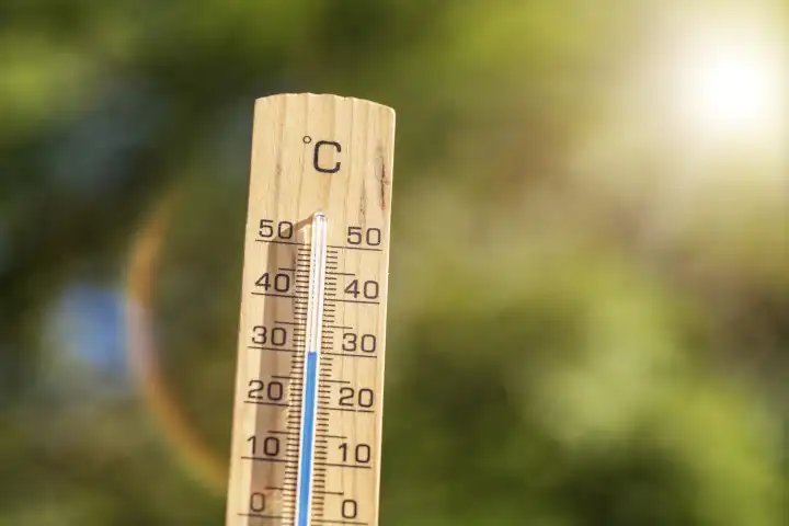 Thermometer aus Holz wird von der Sonne angestrahlt, Temperatur im Sommer bei 30 Grad Celsius