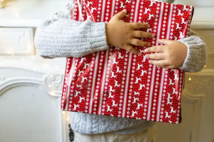 11 August 2023: A child holds a gift wrapped in Christmas wrapping paper. Christmas gift