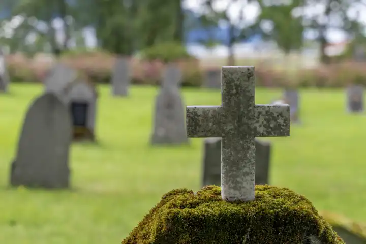 Ein Grabstein auf einem Friedhof mit einem Kreuz aus Stein