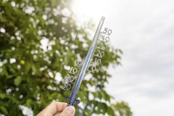 Bavaria, Germany - 25 August 2023: Hand holds thermometer in the sun at 30 degrees Celsius. Summer, sun and heat concept