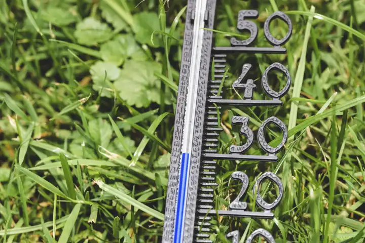 Bavaria, Germany - 25 August 2023: Thermometer in the green meadow at 30 degrees Celsius. Summer, sun and heat concept