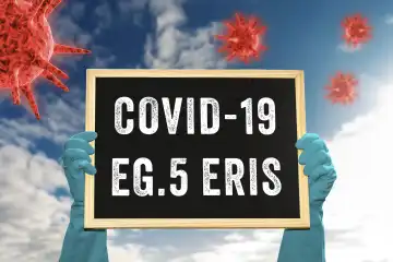 25 August 2023: Hand with protective gloves holds a plaque in the sky in front of Viren with the inscription: Covid-19 EG.5 Eris. New coronavirus mutation PHOTOMONTAGE