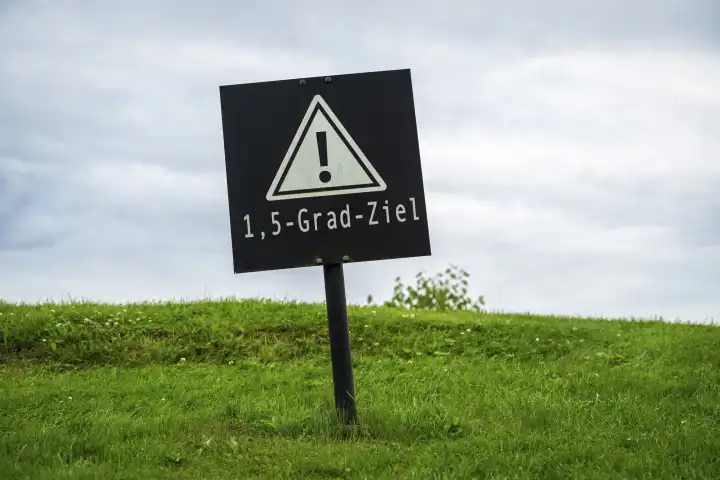26 August 2023: 1.5 degree target, Global warming and environmental protection concept. Warning sign in a meadow with the inscription 1.5 degrees target PHOTOMONTAGE