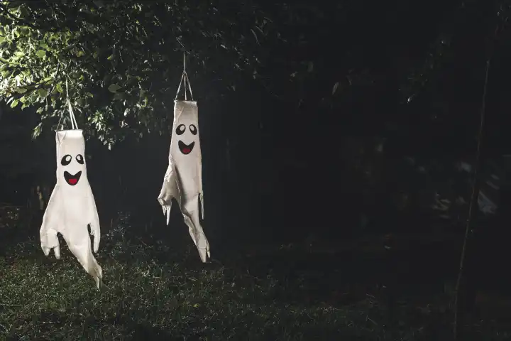 Bavaria, Germany - 26 August 2023: Ghost lanterns hanging in trees in a garden in the dark. ghost lantern, halloween concept