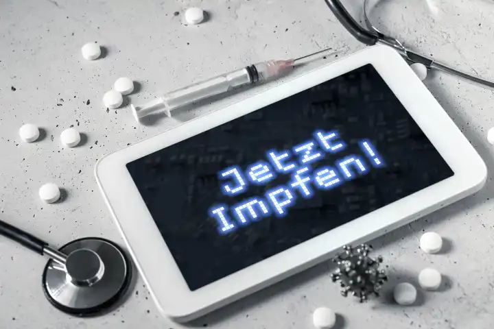 Jetzt Impfen! auf dem Display von einem Tablet Computer. Tabletten, Spritze und Stethoskop mit einem Tablet FOTOMONTAGE
