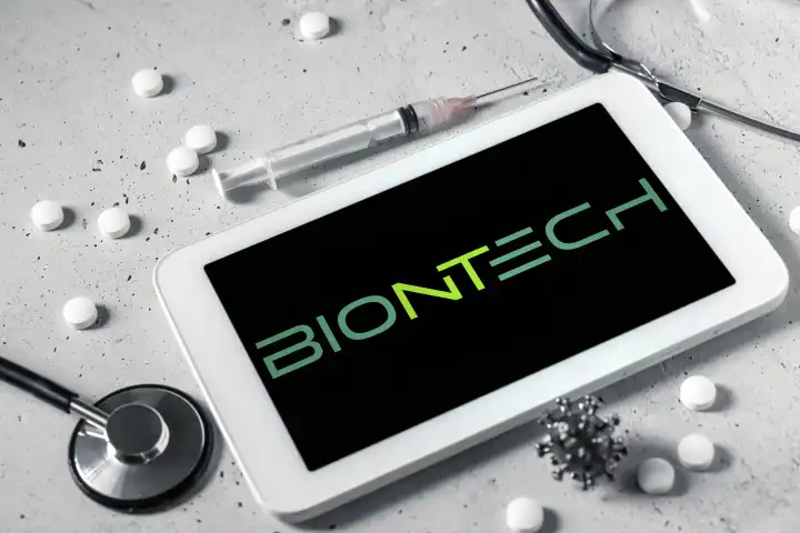 Tablet Computer mit Spritze und Stethoskop mit Biontech Logo auf dem Bildschirm FOTOMONTAGE