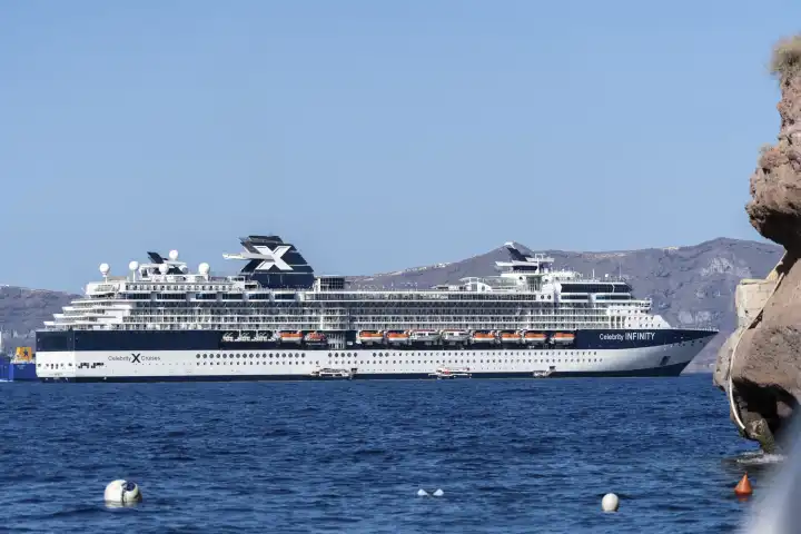 Santorini, Greece - 20 September 2023: The cruise ship of Celebrity Cruises (belongs to Royal Caribbean Cruises) with the ship Celebrity Infinity in the sea in Greece off the island of Santorini