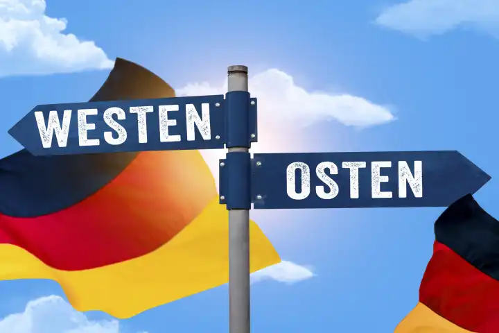 Feiertag und Brückentag Tag der Deutschen Einheit, Himmel mit Deutschland Flagge mit Wegweiser Osten und Westen FOTOMONTAGE