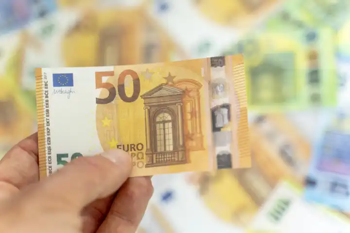 Augsburg, Bavaria, Germany - 5 October 2023: Hand holding a 50 euro cash bill, finance and investment concept