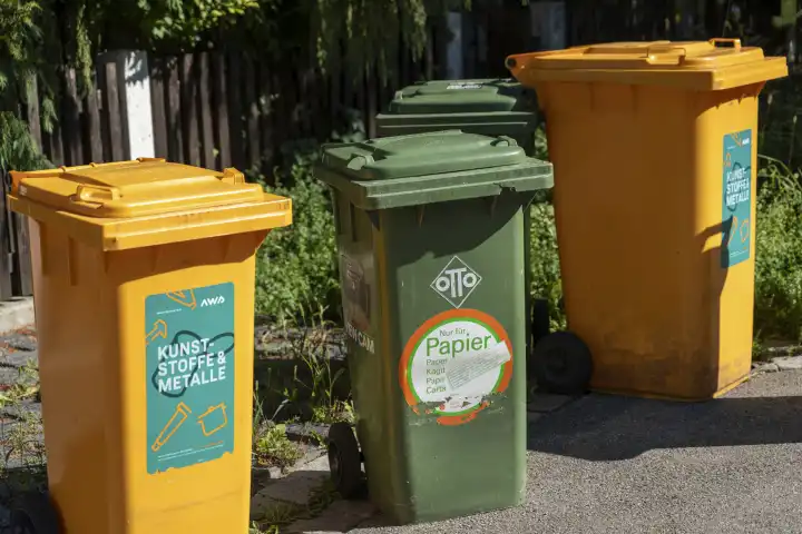 Augsburg, Bavaria, Germany - 7 September 2023: Garbage garbage cans for garbage collection on the street in front of a residential building. Waste separation and recycling concept