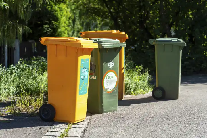 Augsburg, Bavaria, Germany - 7 September 2023: Garbage garbage cans for garbage collection on the street in front of a residential building. Waste separation and recycling concept